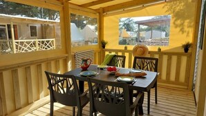 A covered outdoor dining area with a table set for four, surrounded by chairs. - Camping 3 étoiles - Piscine  - ccbfidi (Les Moutiers-en-Retz)