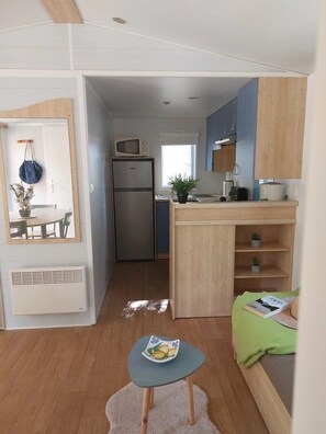 A compact kitchen with a microwave, refrigerator, and wooden cabinets. - Camping 3 étoiles - Piscine  - ccbfidi (Les Moutiers-en-Retz)