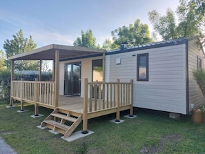 A mobile home with a wooden deck and a covered porch. - Camping 3 étoiles - Piscine  - ccbfie0 (Les Moutiers-en-Retz)