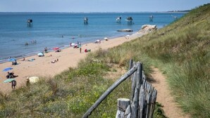Ein Strand mit sandigem Ufer, einer Holzumzäunung und blauem Himmel.