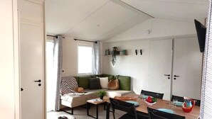 Ein gemütliches Wohnzimmer mit einer Couch, einem Esstisch mit Stühlen, einem kleinen Couchtisch und einem Fenster mit Vorhängen.