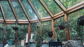 A greenhouse with a wooden frame, potted plants, a table with a notebook, and a rock. - Private Garden Estate, Jacuzzi, Cinema & Games (Southborough)