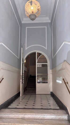 Eine imposante Treppe mit Marmorboden, die zu einem Rundbogen führt.