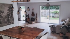 Ein geräumiger Wohnbereich mit einem Holzessttisch, einer Couch und einer großen Schiebeglasdoor zum Garten.