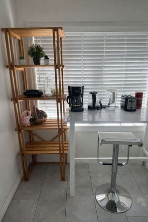 Eine Küche mit einem Holzboden, einer Kaffeemaschine, einem Toaster und einem Wasserkocher.