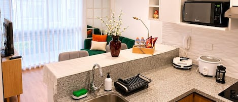 A modern kitchen with granite countertops, a built-in microwave, a coffee maker, and a slow cooker.