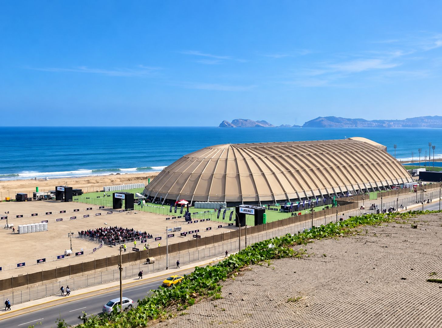 Un estadio con un techo grande y curvo, situado cerca de una playa y el océano al fondo.