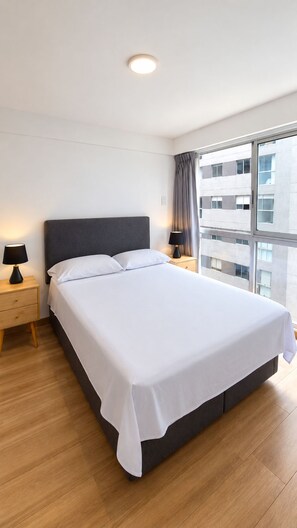 A modern hotel room with a large bed, a nightstand, a lamp, and a view of the city through large windows. - Loto Stays Apartment across from Costa21 | Arena1 | Self-check-in (San Miguel)