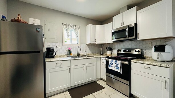 A kitchen with white cabinets, stainless steel appliances, a microwave, a toaster, and a coffee maker. - Cozy 1-bedroom apartment in nice Houston with AC (Houston)