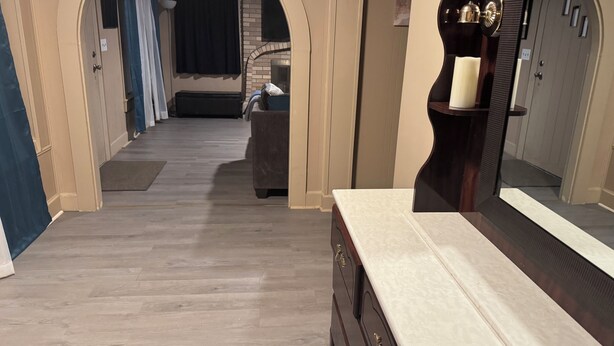 A hallway with a wooden floor, a dark-toned dresser with drawers, and a large mirror. - Large, comfortable home, great location, 4 bedroom, washer/dryer, pet friendly (Mobile)