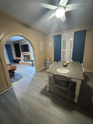 A dining area with a table, chairs, a ceiling fan, and a fireplace. - Large, comfortable home, great location, 4 bedroom, washer/dryer, pet friendly (Mobile)