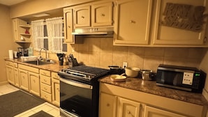 A kitchen with beige cabinets, a black stove, a microwave, and a sink. - Large, comfortable home, great location, 4 bedroom, washer/dryer, pet friendly (Mobile)