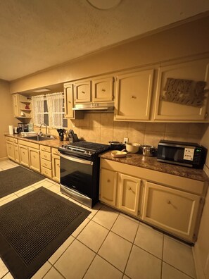 A kitchen with beige cabinets, a black stove, a microwave, and a sink. - Large, comfortable home, great location, 4 bedroom, washer/dryer, pet friendly (Mobile)