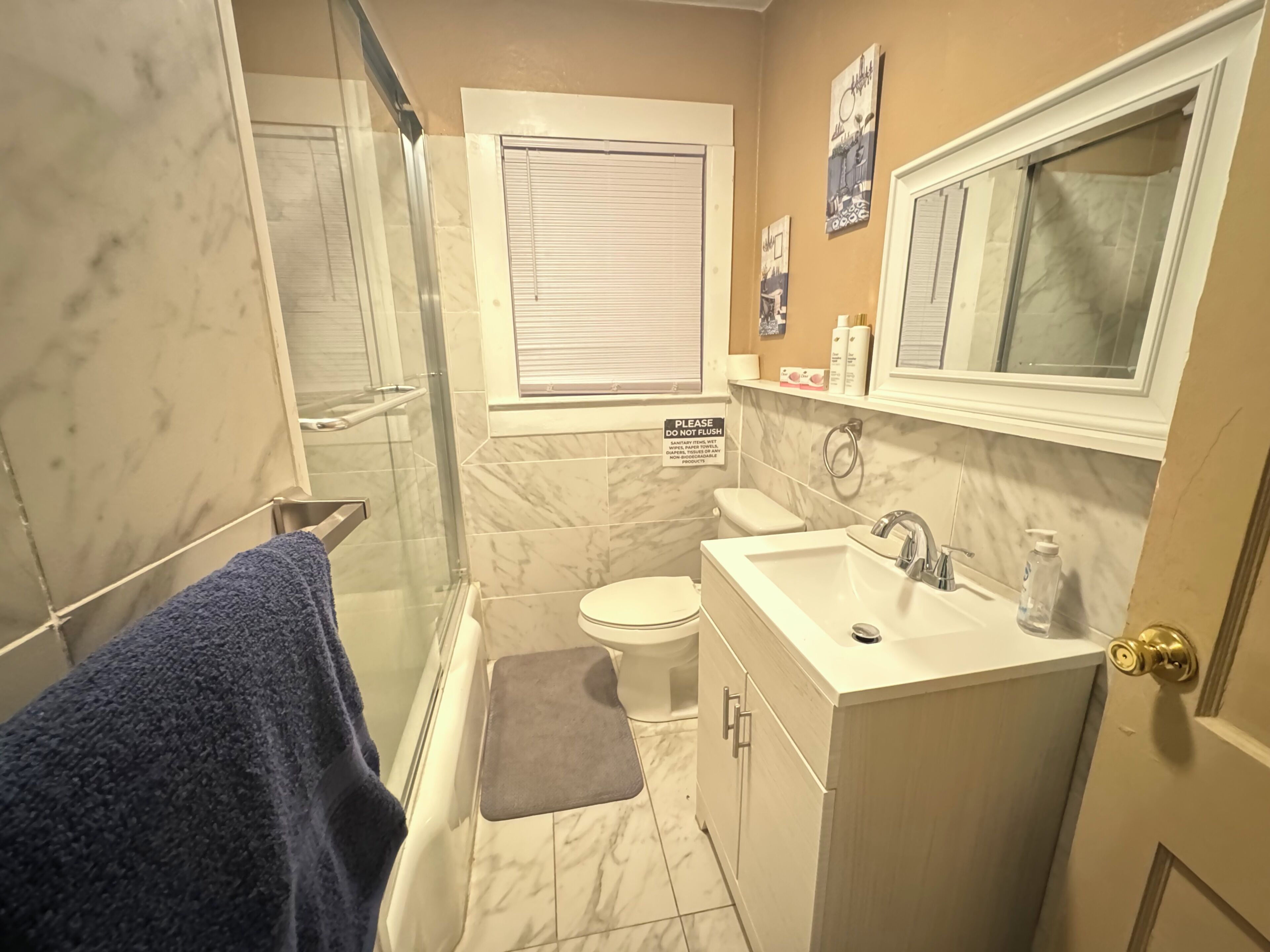A bathroom with a shower, toilet, sink, and a towel rack.