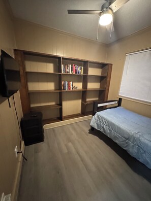 A bedroom with a bed, a bookshelf, a ceiling fan, and a window. - Large, comfortable home, great location, 4 bedroom, washer/dryer, pet friendly (Mobile)