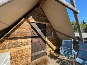 A wooden cabin with a sloped roof, a door, and two chairs. - Camping 3 étoiles - Piscine  - ccbgcdc (Plats)