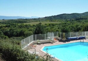 A swimming pool with a fenced area, surrounded by greenery and hills in the background. - Camping 3 étoiles - Piscine  - ccbgcdc (Plats)