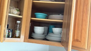 A kitchen with a microwave, a kettle, and a cabinet with dishes and food items. - LA JOLLA PRIVATE STUDIO (San Diego)