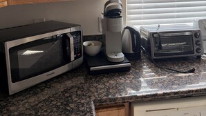 A kitchen with a microwave, coffee maker, toaster, and a cabinet with storage items. - LA JOLLA PRIVATE STUDIO (San Diego)
