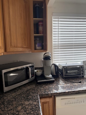 A kitchen with a microwave, coffee maker, toaster, and a cabinet with storage items. - LA JOLLA PRIVATE STUDIO (San Diego)