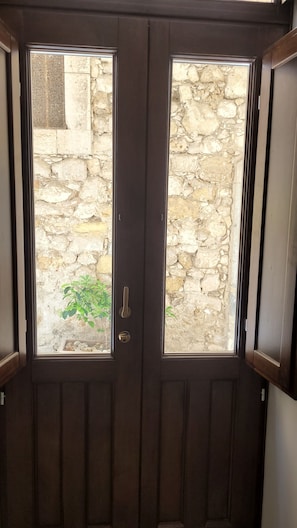 Una puerta de madera oscura sobre un fondo de pared de piedra y una pequeña ventana.