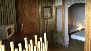 Une pièce rustique en bois, avec un lit, une petite table, un tableau encadré et un four à micro-ondes.