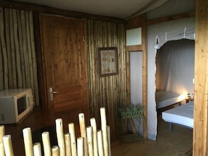 Ein rustikaler Holzraum mit einem Bett, einem kleinen Tisch, einem gerahmten Bild und einer Mikrowelle.
