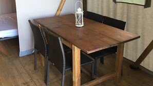 Une table à manger en bois, des chaises, une lanterne blanche et une fenêtre avec des rideaux.