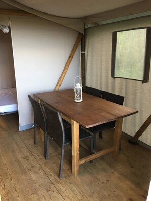 Ein Holzespeisesaal mit Stühlen, einer weißen Laterne und einem Fenster mit Vorhängen.