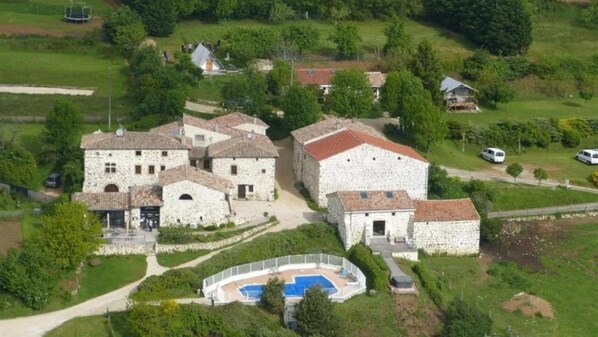 A stone building complex with multiple structures, a swimming pool, and surrounding greenery. - Camping 3 étoiles - Piscine - ccbgcdf (Plats)
