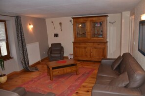 A living room with a brown leather sofa, a wooden coffee table, a brown leather chair, a wooden cabinet with glass doors, and a patterned rug. - Camping 3 étoiles - Piscine  - ccbgbcb (Plats)