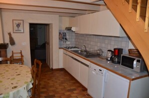 Een kleine keuken met een vaatwasser, magnetron en gasfornuis.