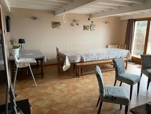 Ein Zimmer mit einem Bett, einem Tisch, Stühlen, einer Zimmerpflanze und Bildern an der Wand.