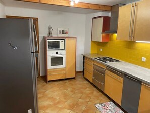 Eine kompakte Küche mit Kühlschrank, Mikrowelle, Backofen, Herd und Schränken.
