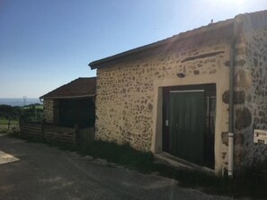 Ein Steinhaus mit einer dunklen Tür und einem kleinen Fenster.