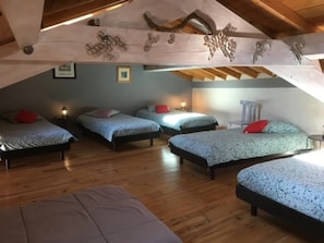 A loft bedroom with four beds, wooden beams, and a sloped ceiling. - Camping 3 étoiles - Piscine  - ccbgcdh (Plats)
