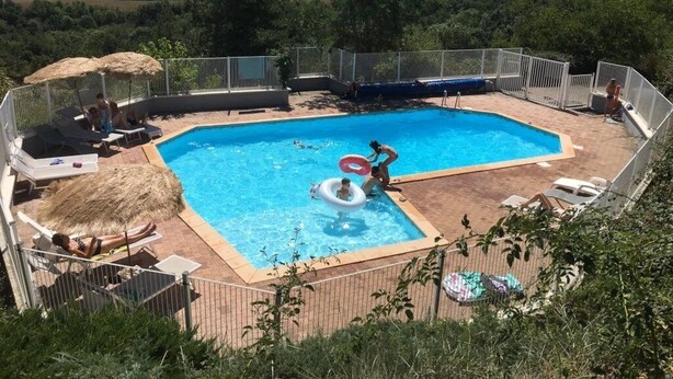 A swimming pool with a view of the countryside, surrounded by lounge chairs and a fence. - Camping 3 étoiles - Piscine  - ccbgcdh (Plats)