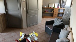 A living room with a sofa, a small table, and a toy horse. There is a door and a shelf with books and a water bottle. - Camping 3 étoiles - Piscine  - ccbgcdh (Plats)