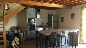 A kitchen with a central island, bar stools, a staircase, and a sofa. - Camping 3 étoiles - Piscine  - ccbgcdh (Plats)
