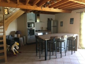 Eine Küche mit Kochinsel, Barhocker, einer Treppe und einer Couch.