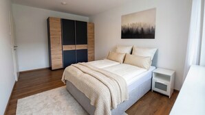 Ein Schlafzimmer mit Bett, Nachttisch, Kleiderschrank und einem Gemälde an der Wand.