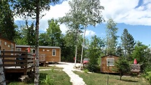Un terrain de camping doté de cabanes en bois, d’un sentier de gravier et entouré d’arbres.