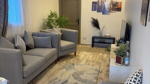 A modern living room with a grey sofa set, a patterned rug, and a wooden floor. - Perfect 1-bedroom apartment with AC in superb Giza Governorate (Giza Governorate)