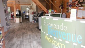 En reception med et 'Bienvenue'-skilt, en disk og en trappe op til øvre etager.