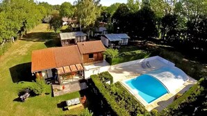 Una propiedad residencial con piscina, terraza cubierta y garaje independiente.