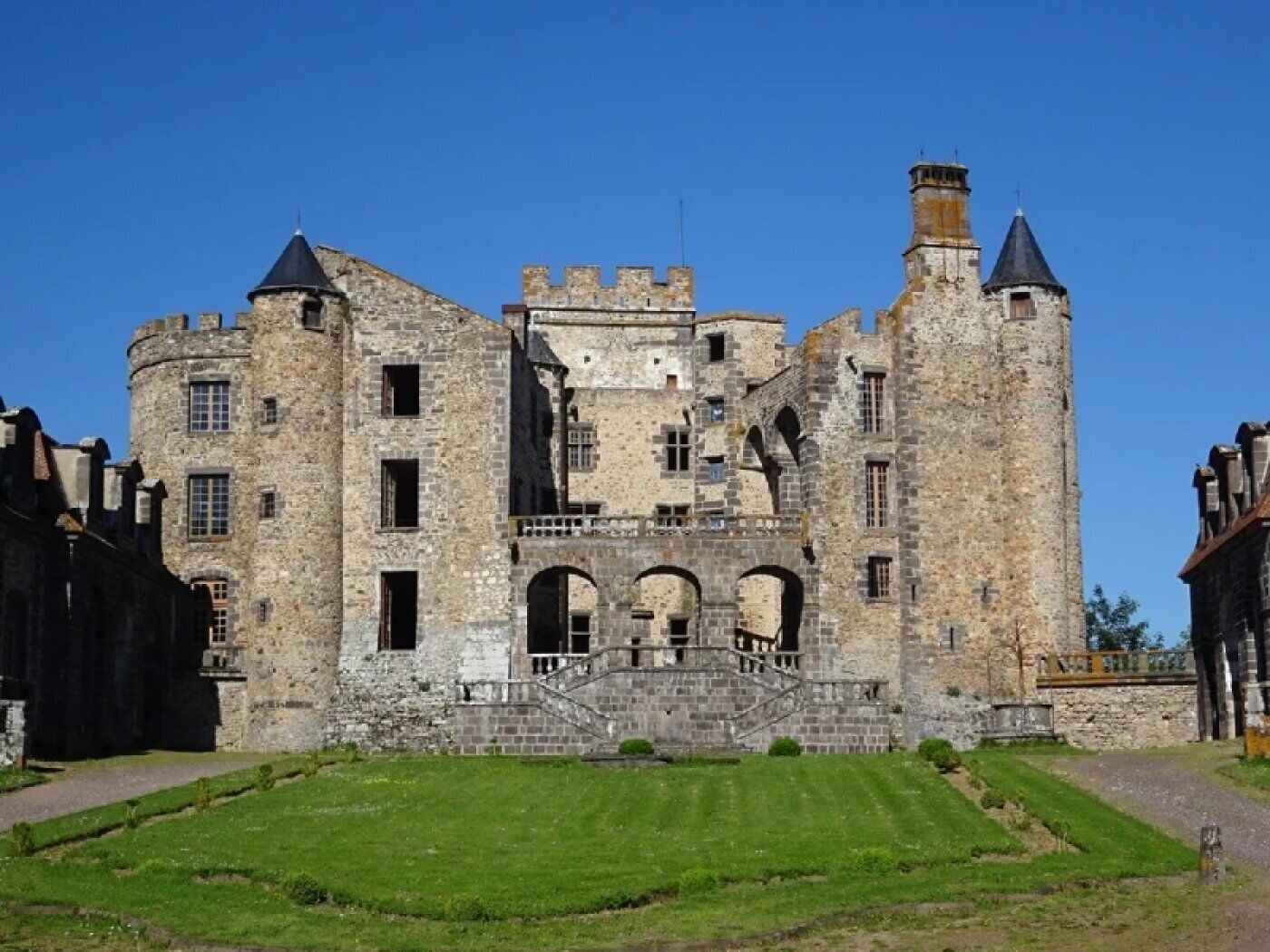 A historic stone castle with multiple towers, arched windows, and a central courtyard.