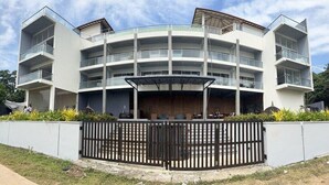 A multi-story building with balconies, a gated entrance, and a covered outdoor area.