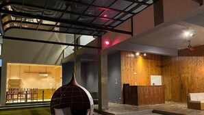 A modern interior with a reception desk, a hanging chair, and a staircase leading to an upper level.