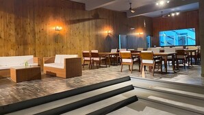 A modern interior with wooden walls, a staircase, and a seating area with tables and chairs.