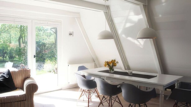 A modern dining area with a white table, grey chairs, and pendant lights. - Modern, cozy vacation home with a fireplace, sauna, and large garden (Winsen (Aller))